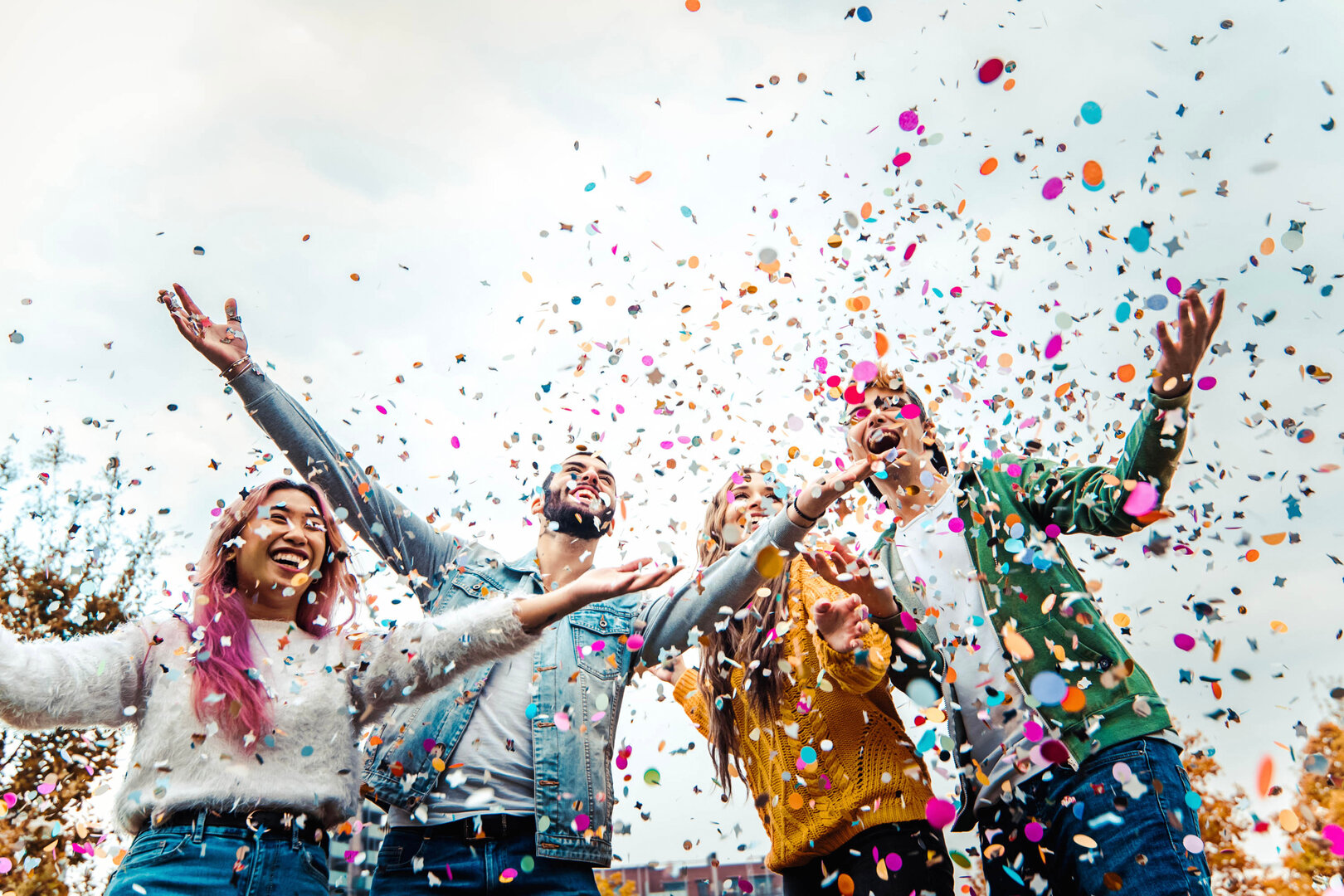 Happy friends celebrating throwing confetti in the air - Young p Students having fun together at college campus throwing confetti in the air