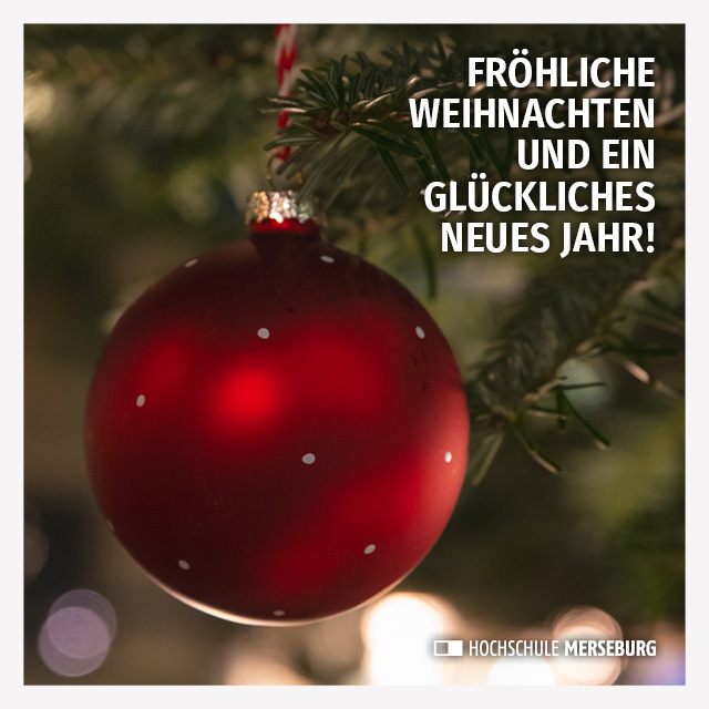 Eine große, rote, matt-glänzende Weihnachtskugel mit kleinen, weißen Punkten hängt an einem Tannenzweig eines Weihnachtsbaumes. Die Atmosphäre ist dunkel und gleichzeitig festlich erleuchtet. Als Gruß ist zu lesen: "Fröhliche Weihnachten und es glückliches neues Jahr!"