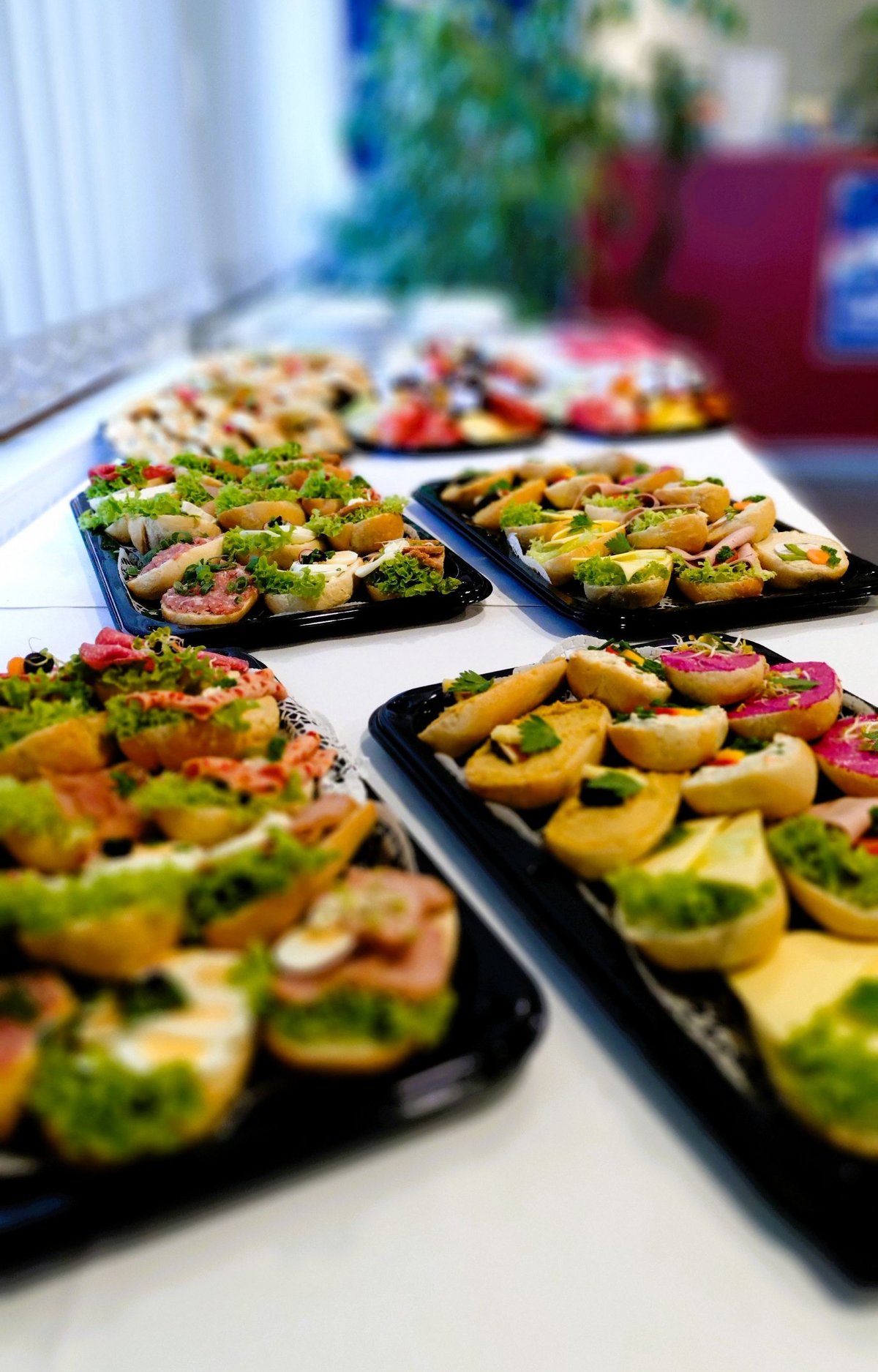 belegte Brötchen auf schwarzen Tellern auf Tisch mit weißer Tischdecke