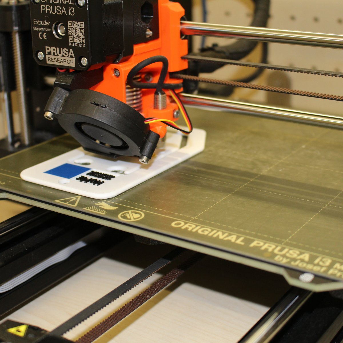 Zu sehen ist ein 3D-Drucker, welcher mit weißem Filament ein Produkt druckt. 