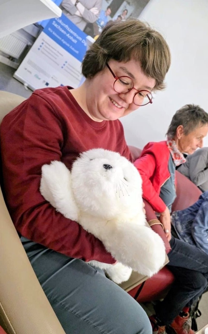 Alumna sitzend mit der Assistenzrobe im Arm