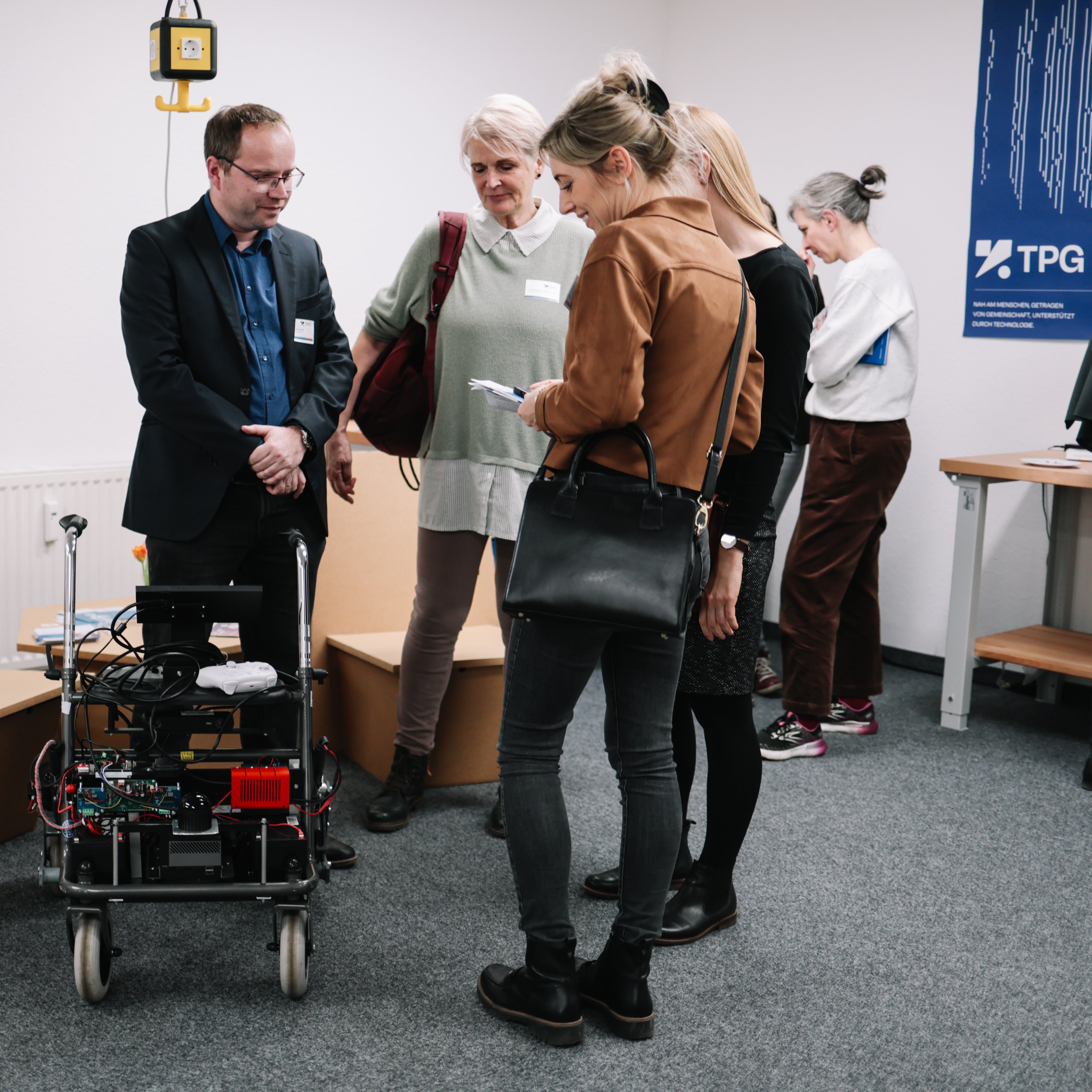 Personen schauen sich einen intelligenten Rollator an.