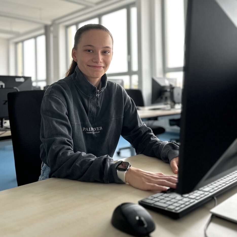 Eine Person sitzt am Tisch vor einem Bildschirm