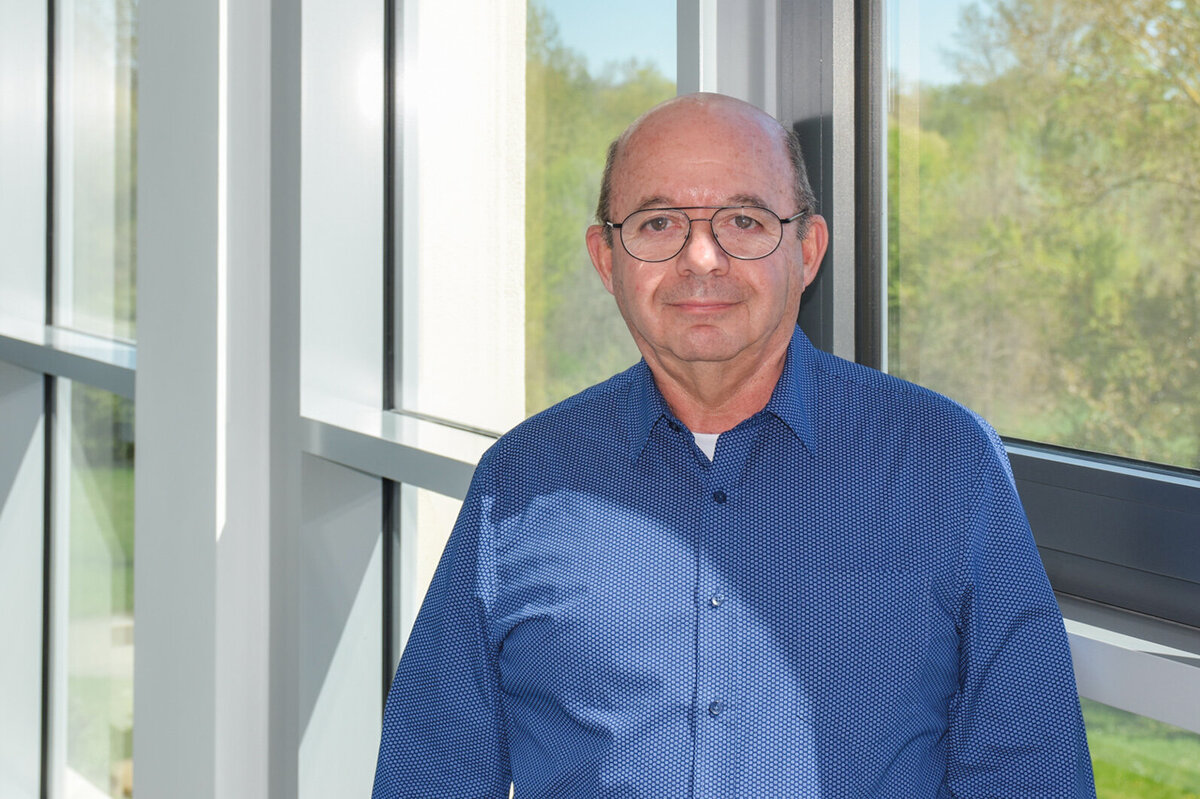 Prof. Coello Machado steht in einem Gang und lächelt in die Kamera