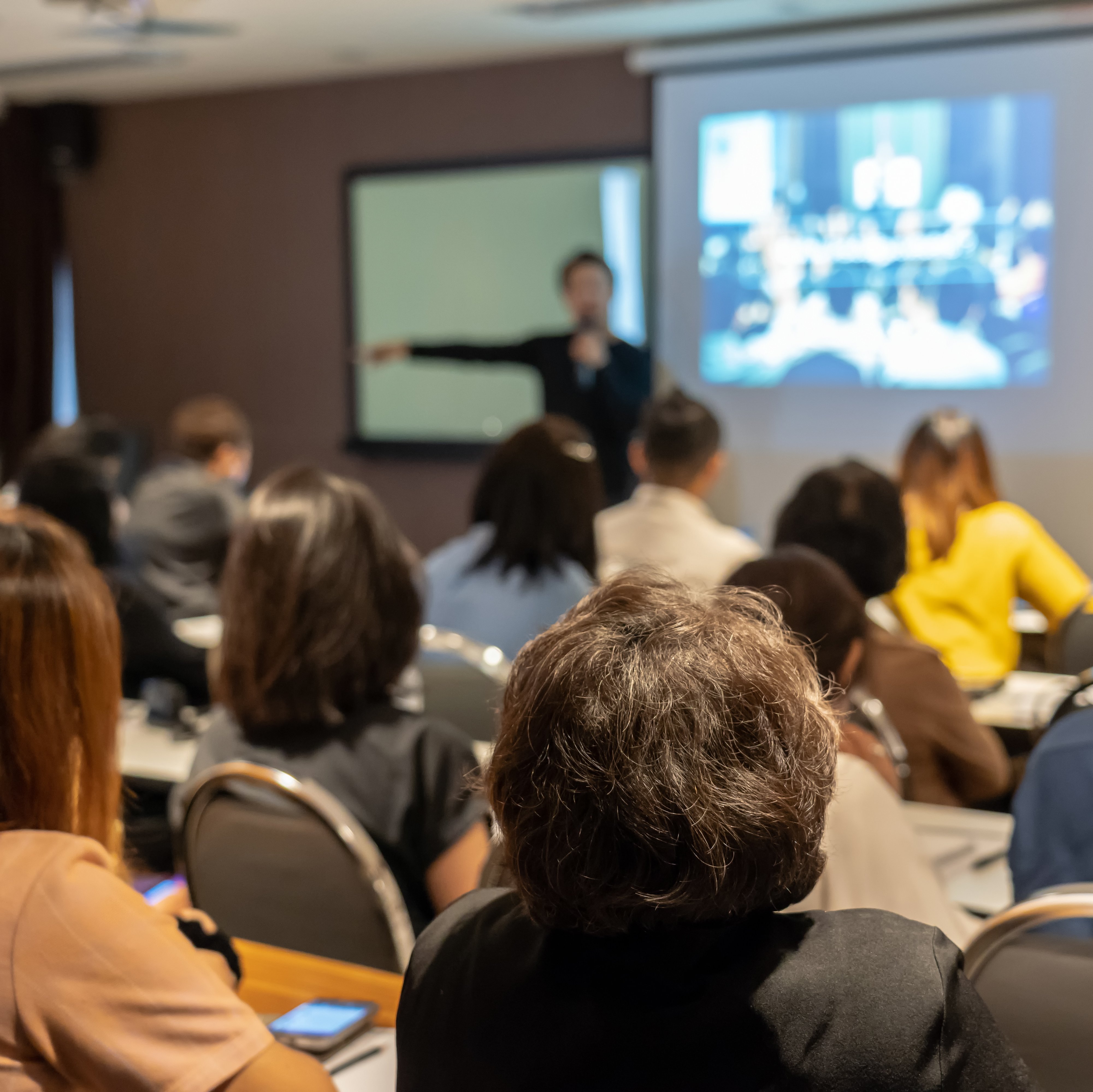 Disputationsvortrag Person hält einen Vortrag vor einer Gruppe von Zuschauenden