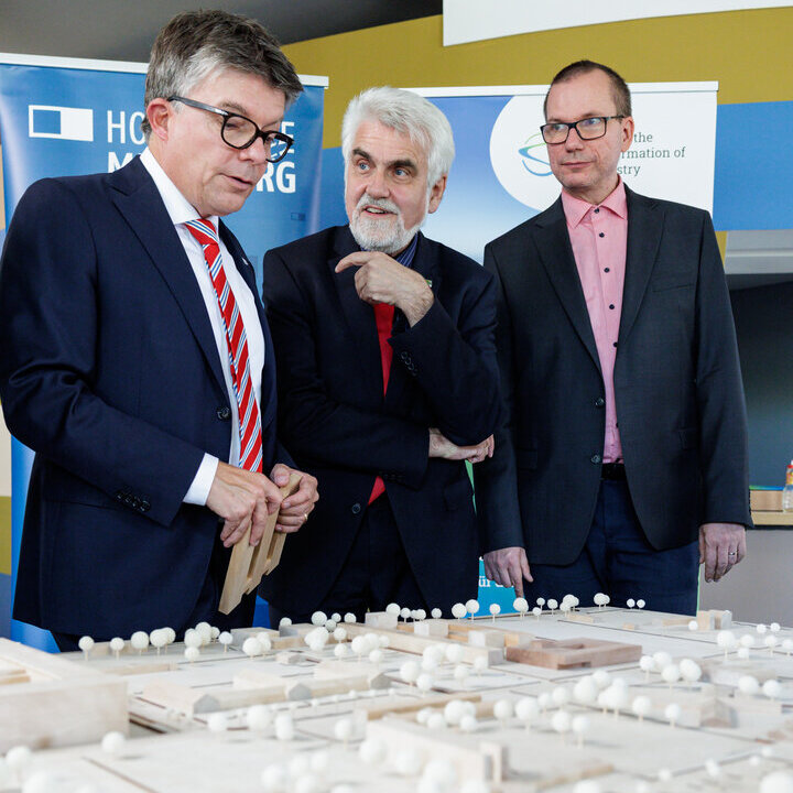 Minister Prof. Dr. Armin Willingmann (Mitte) und kommissarischer Rektor der Hochschule Merseburg Prof. Dr. Heinz-Jürgen Voß (rechts) lassen sich das Campusbauvorhaben vom CTC-Geschäftsführer Christian Harringa erläutern 3 Personen unterhalten sich