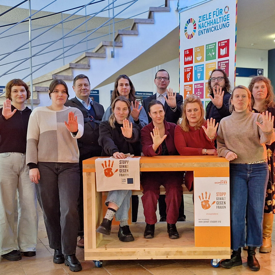 Das Bild zeigt mehrere Personen das Hand-Symbol des Orange Day zeigen