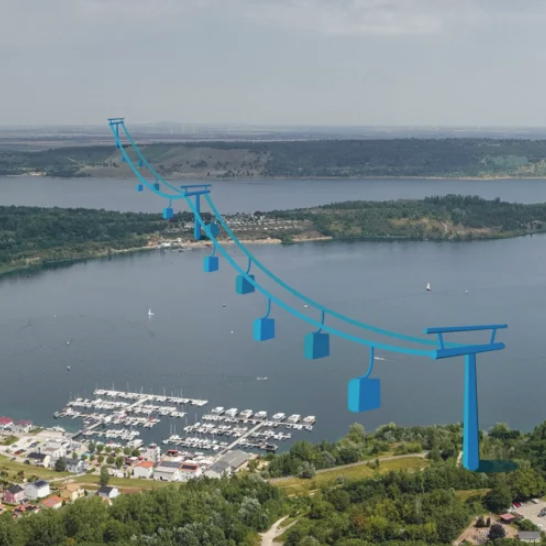 Zu sehen ist ein See über den eine Seilbahn führt. 