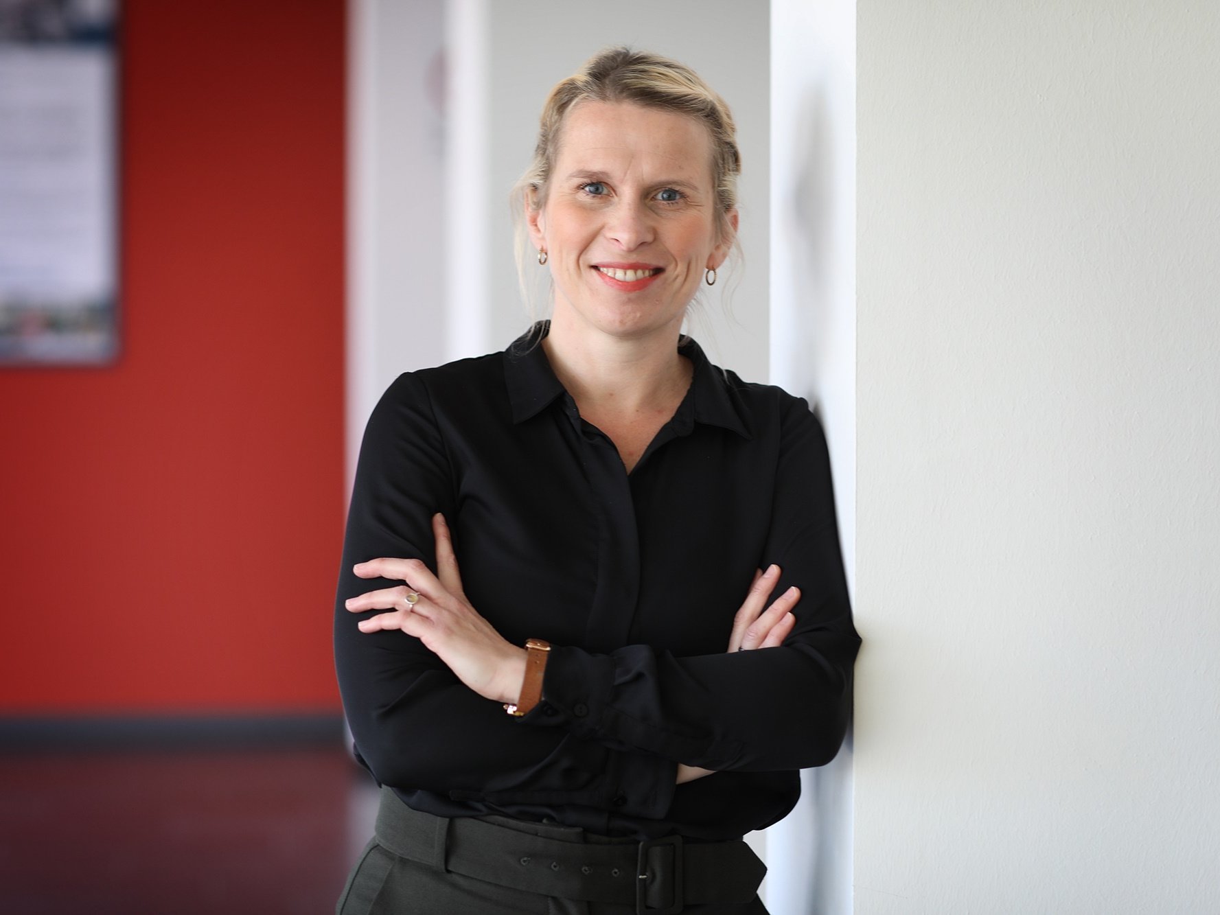 Person lehnt mit verschränkten Armen an einer weißen Wand