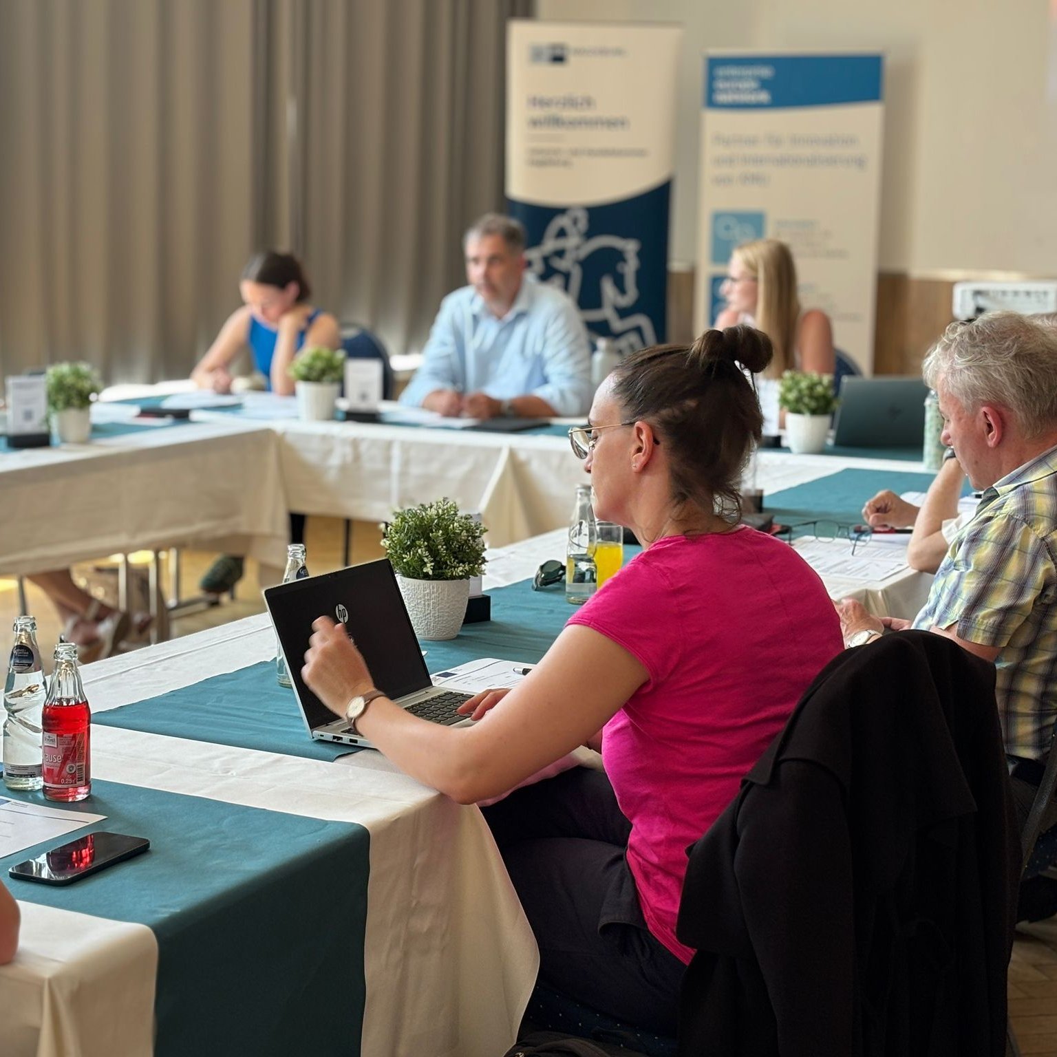 Es sitzen mehrere Personen an einem Tisch und nehmen an der EEN-Konferenz teil.