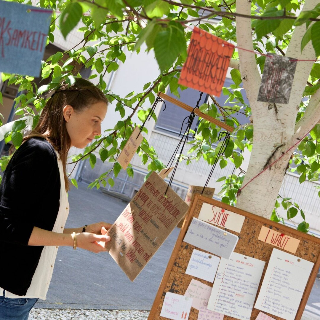 Person vor einem Baum mit buten Zetteln