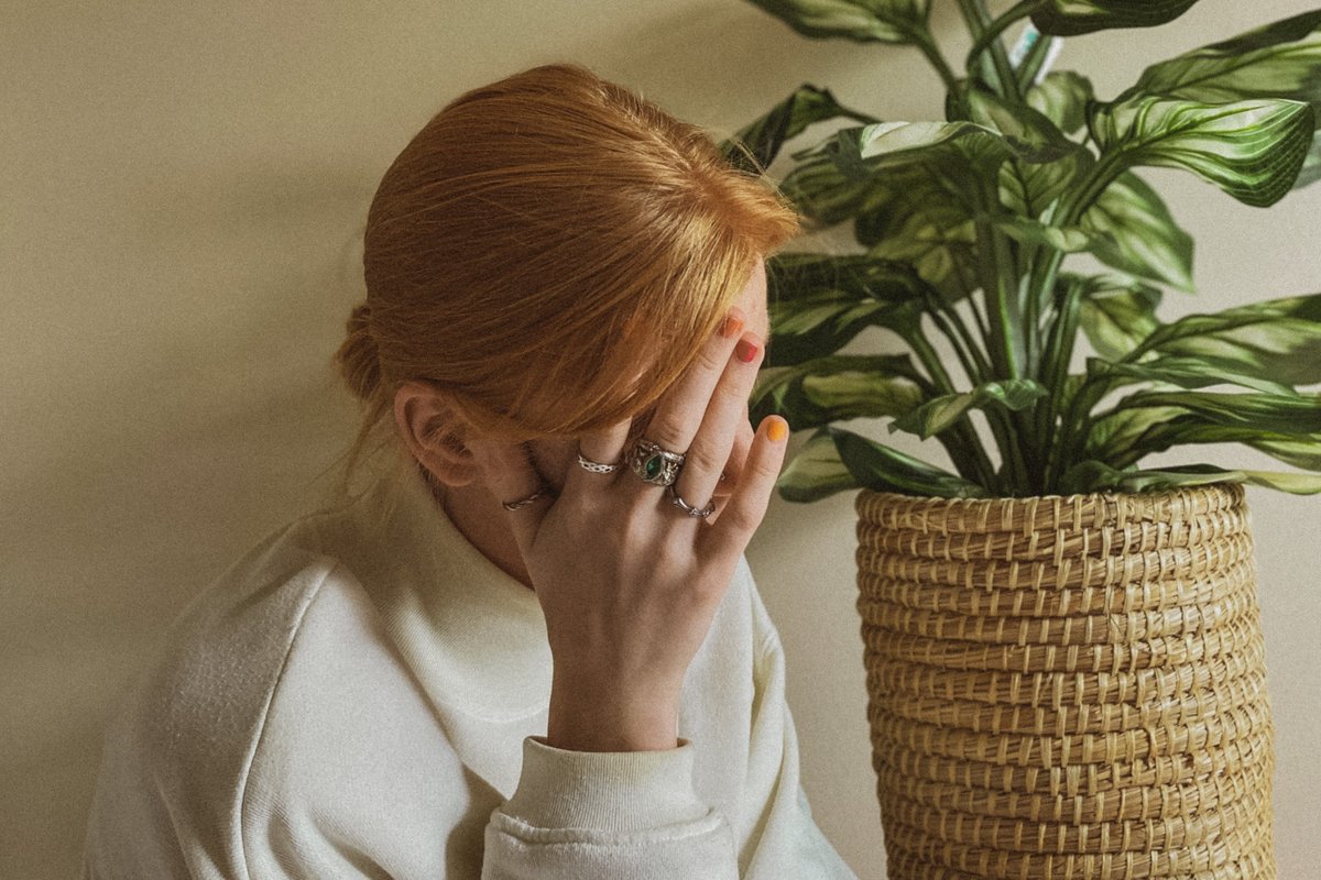 Eine Frau die ihre Hand an ihre Stirn hält und sichtlich erschöpft ist.