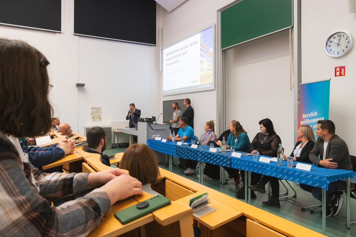 blauer Tisch mit Personen im Hörsaal