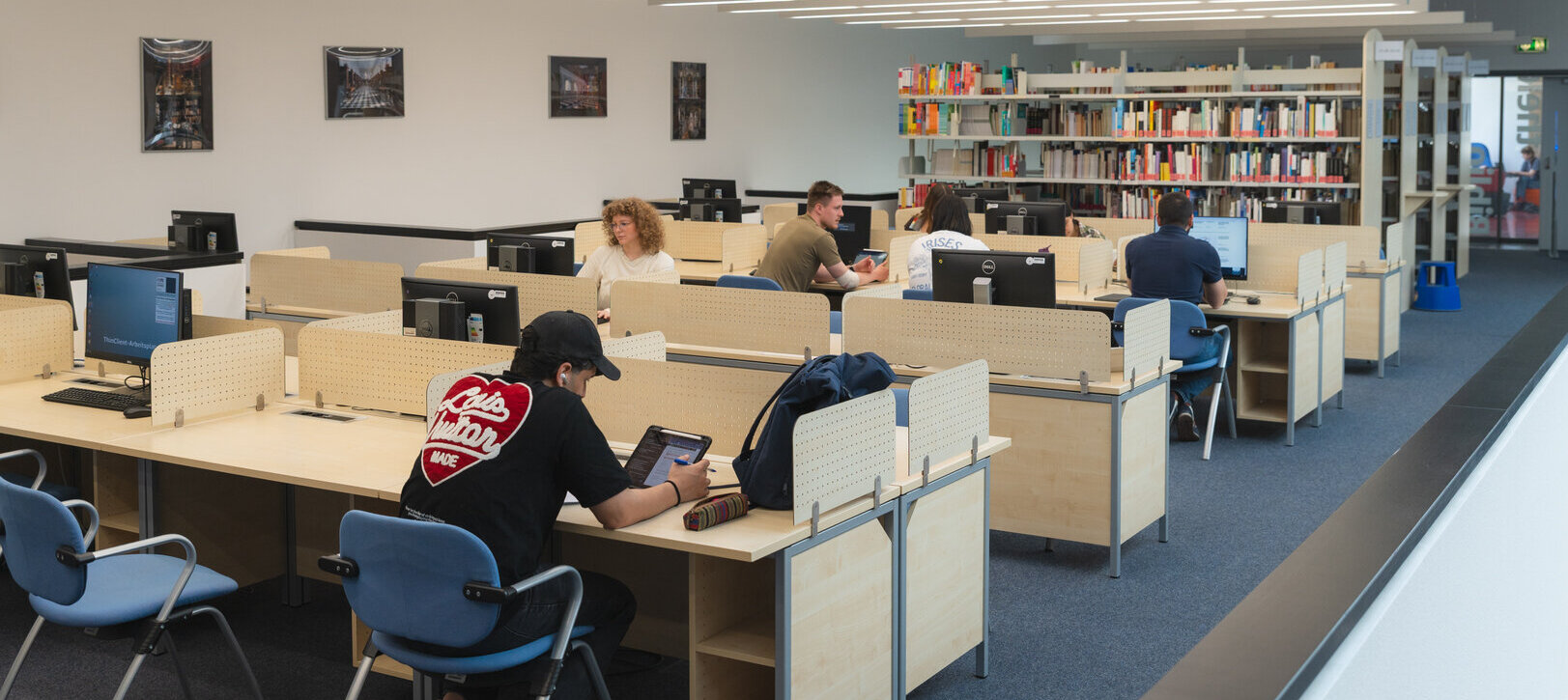 Bibliotheksbild mit Arbeitsplätzen und Regale mit Büchern