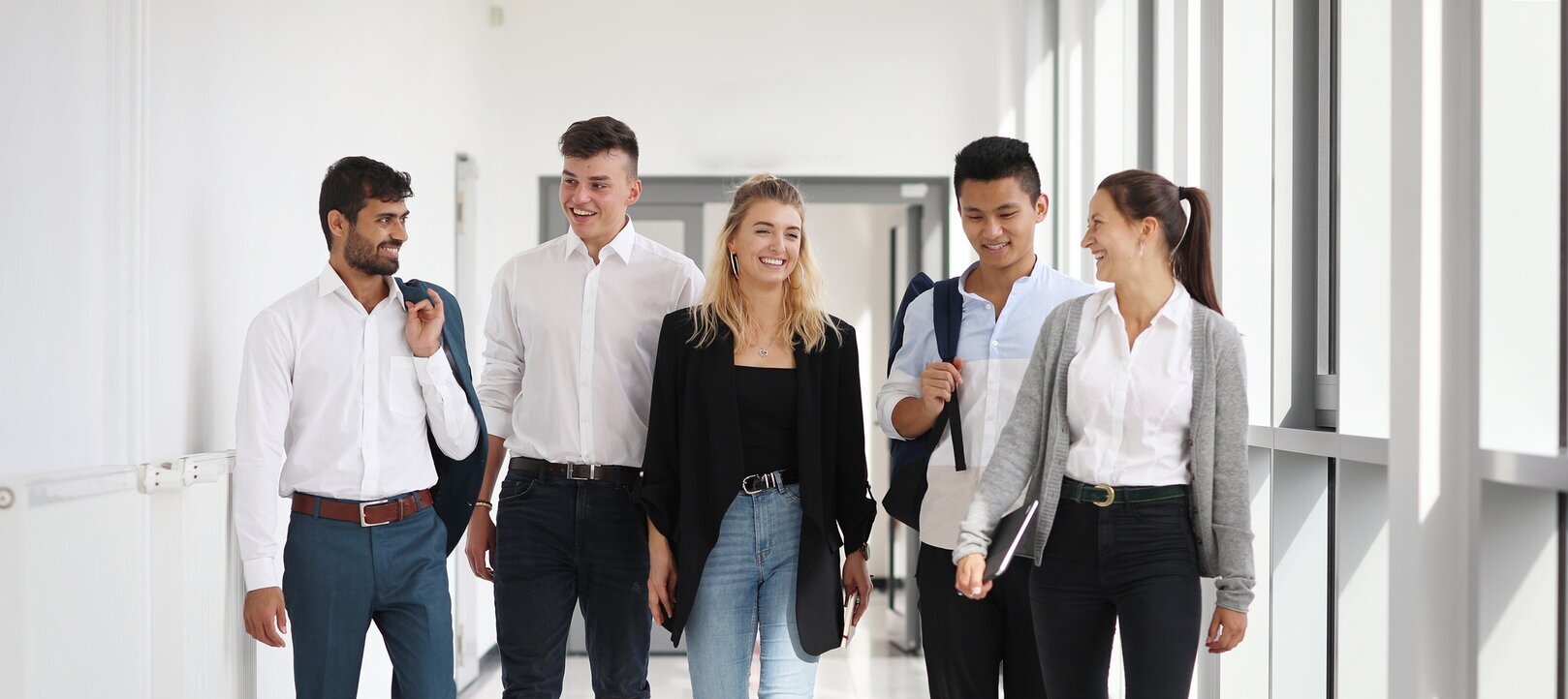 Fünf junge Menschen laufen durch einen Flur an der Hochschule Merseburg.