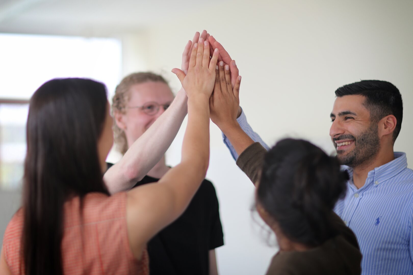 Vier Menschen halten ihre rechte Hand in der Luft zusammen