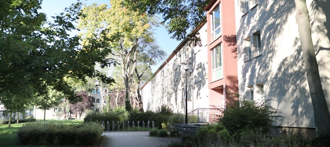 Aussenansicht eines Gebäudes mit Bäumen in der Sonne