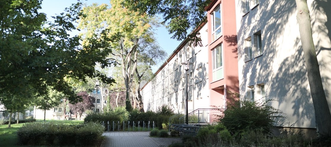 Aussenansicht eines Gebäudes mit Bäumen in der Sonne