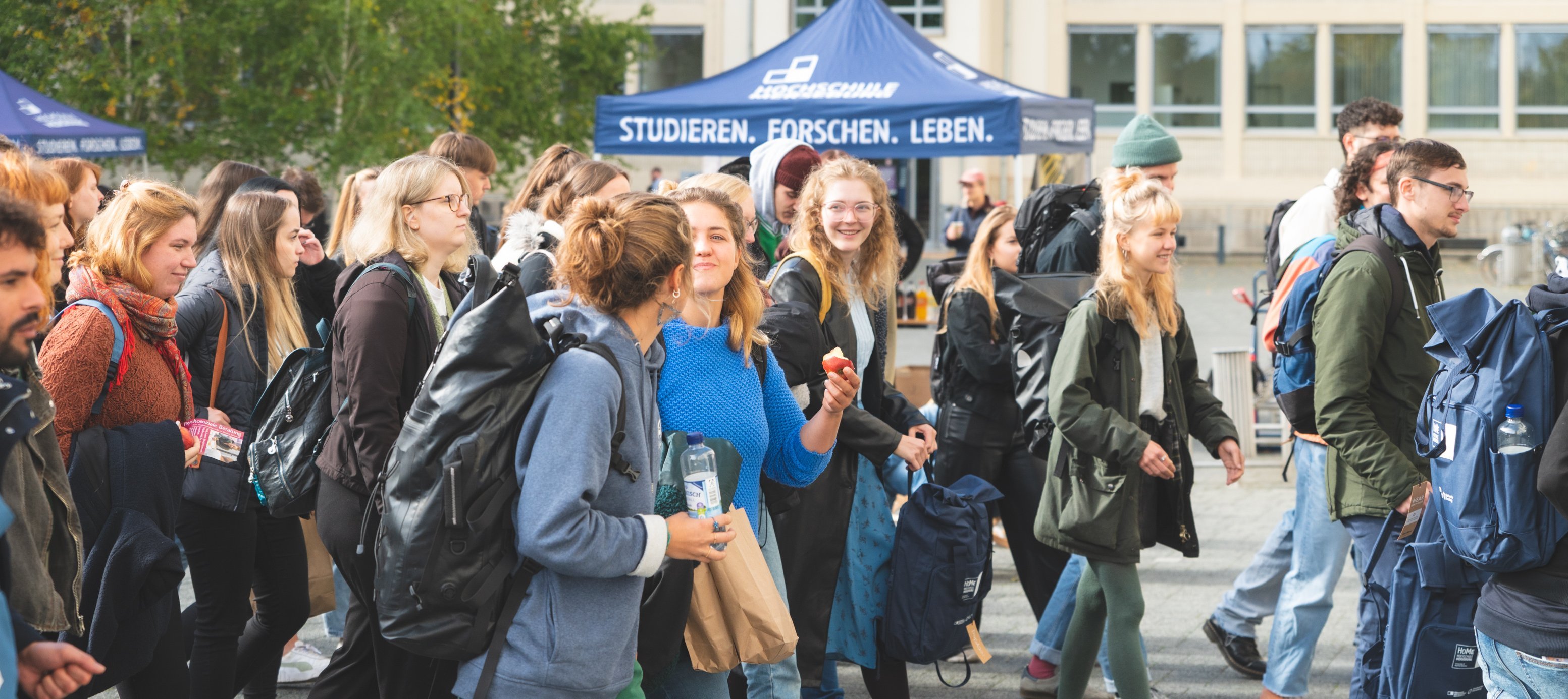 Header-Fotos Bildsprache Header-Foto: Eine große Gruppe Studierender läuft über den Innenhof der Hochschule.
