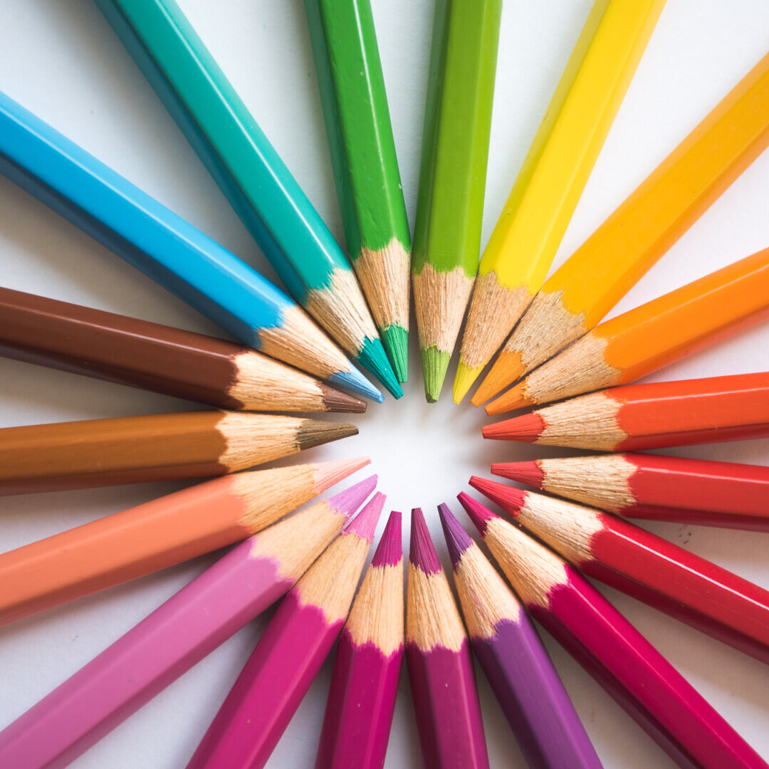 Bunte Stifte die in einem Kreis mit der Spitze in die Mitte zusammengelegt sind