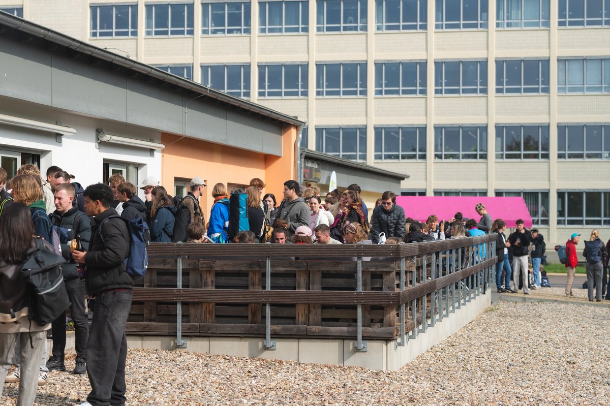Personen auf einer Terasse vor einem Gebäude