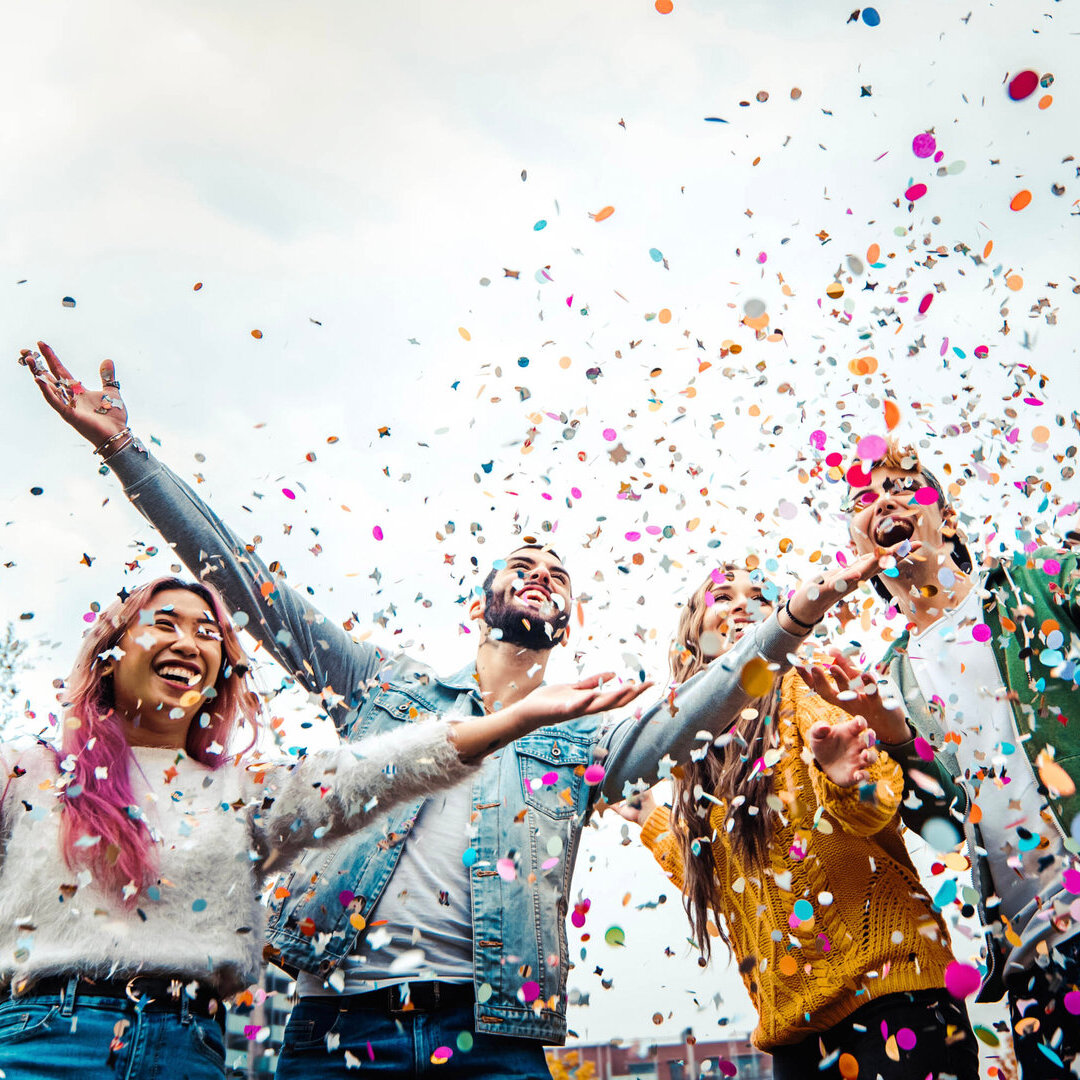 Students having fun together at college campus throwing confetti in the air