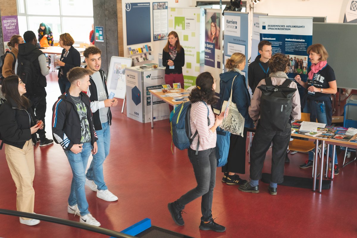 Studierende an Informationsstände im Foyer vor der Bibliothek