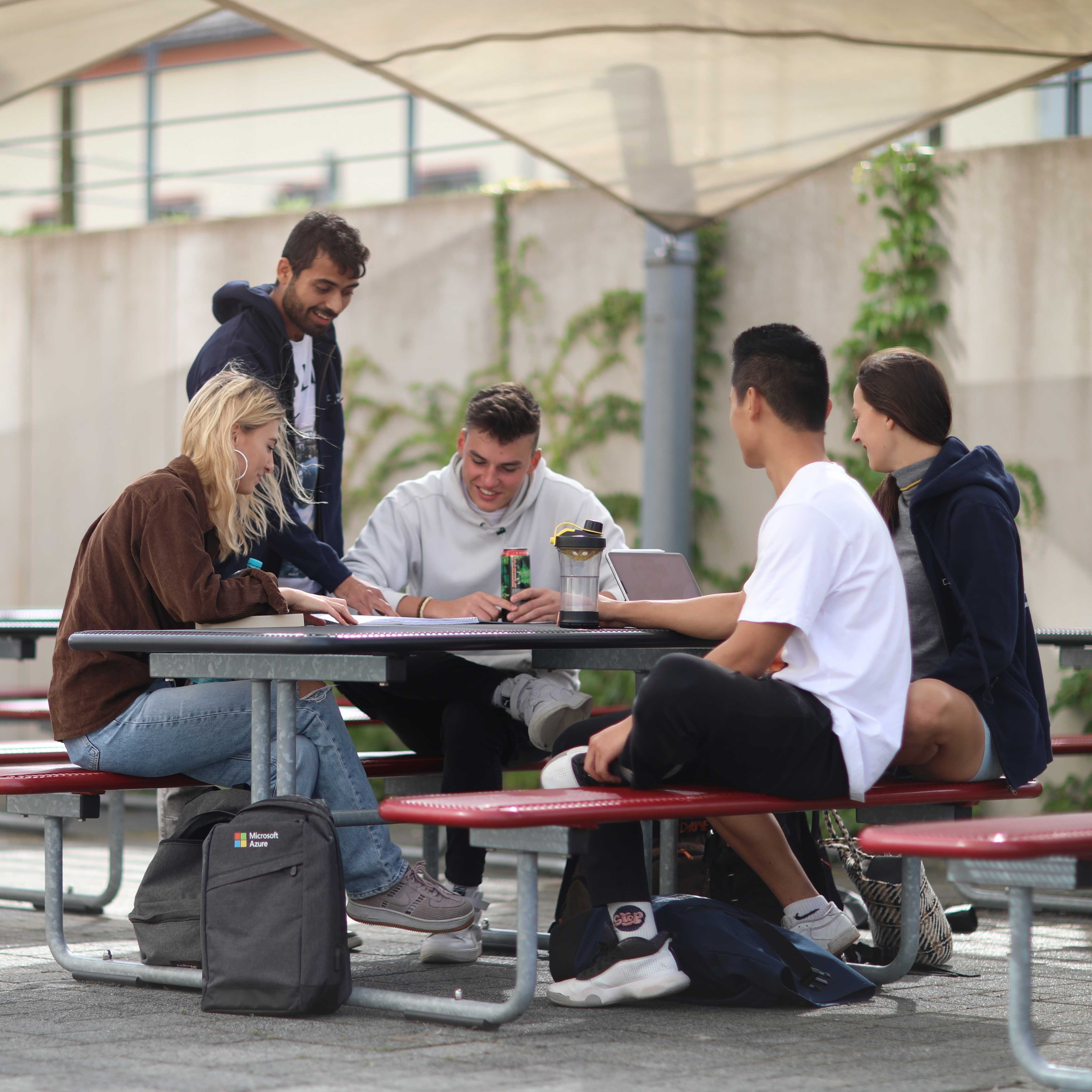 Studierende sitzen im freine an einem Tisch