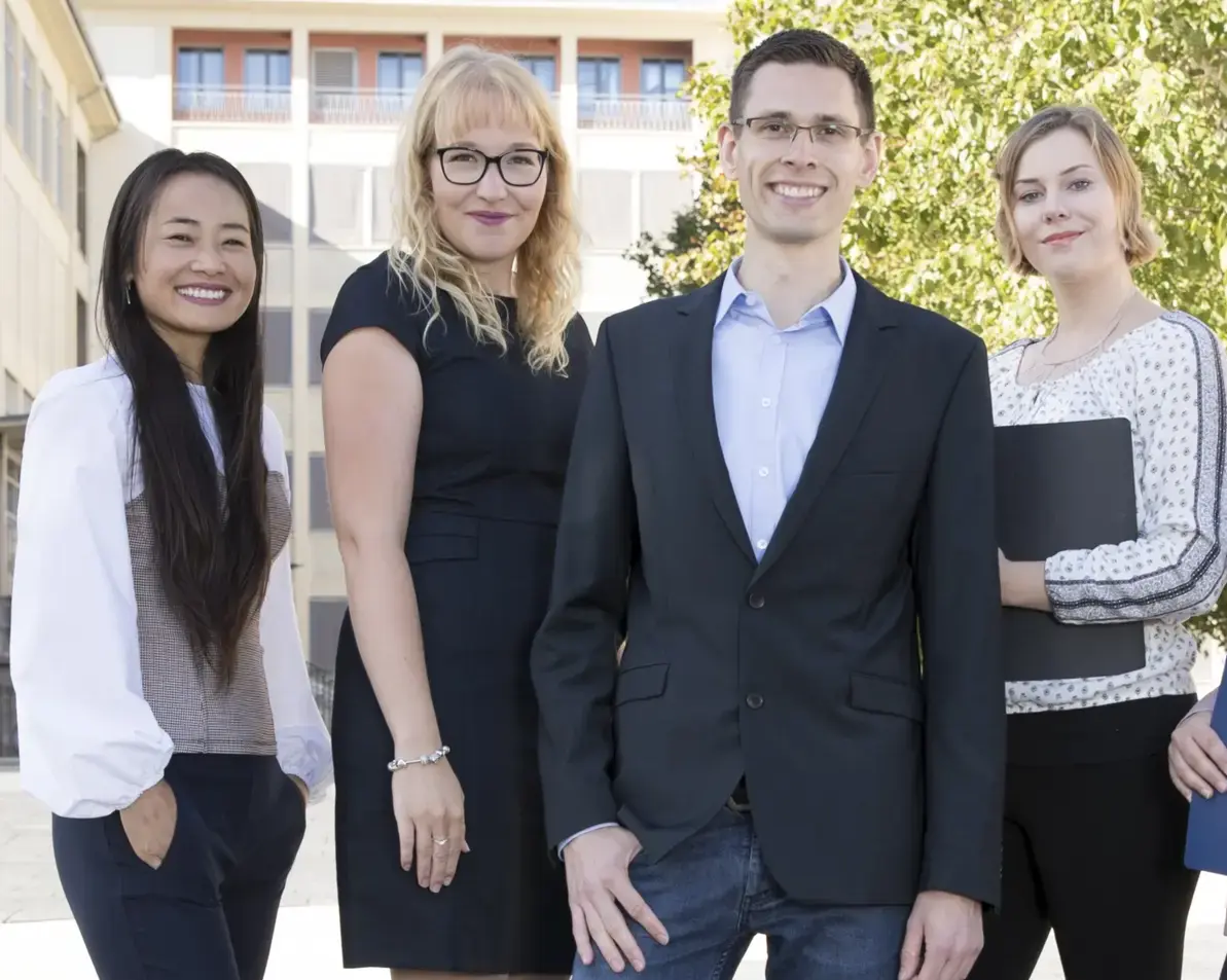 Vier Personen im Business-Look schauen in die Kamera.