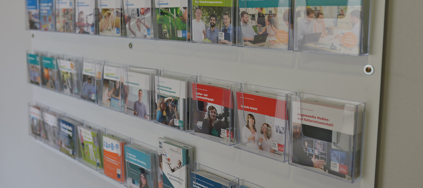 Foto von einer Ablage an der Wand mit verschiedenen Flyern und Broschüren